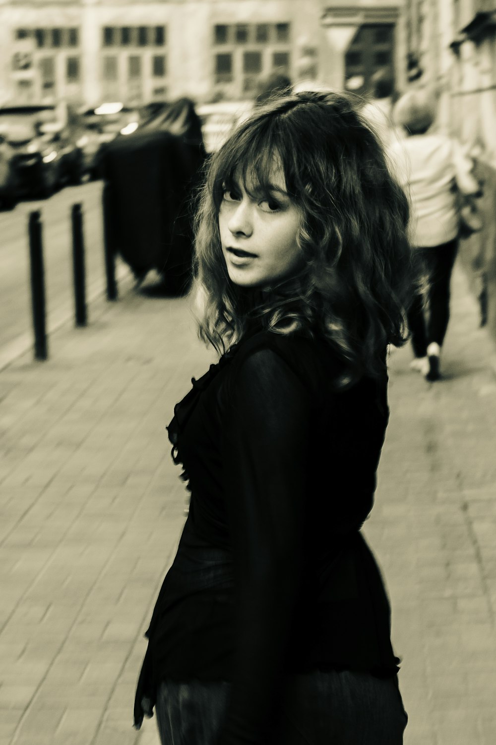 a woman standing on a sidewalk in a black dress