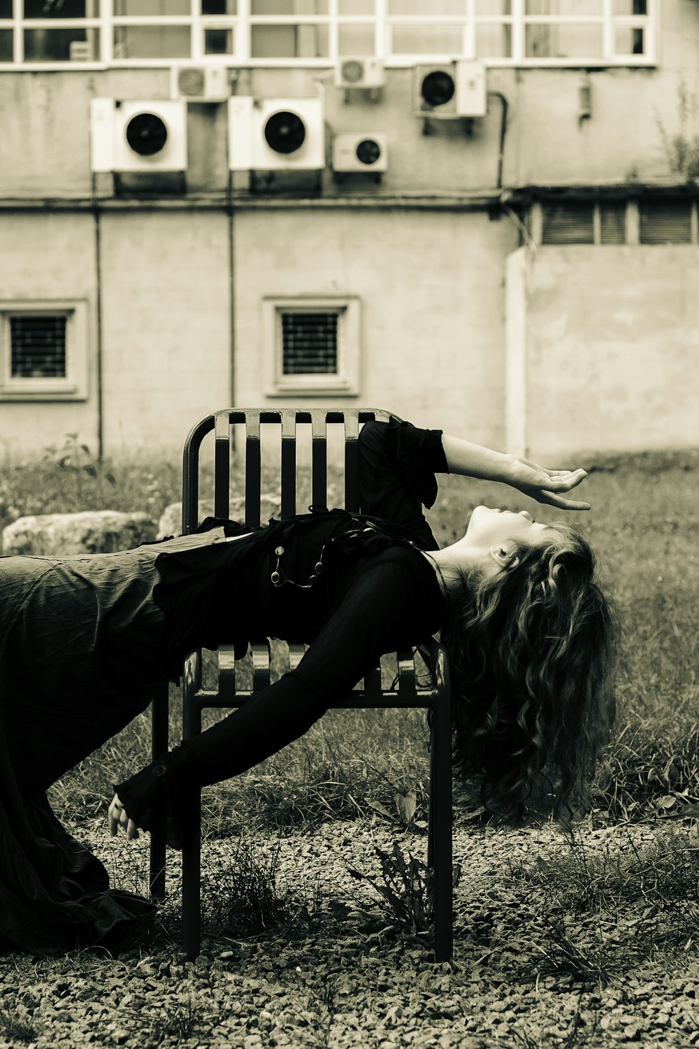 a black and white photo of a woman laying on a bench