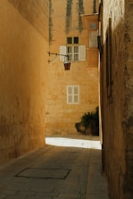 a narrow alley way with a lamp on the wall