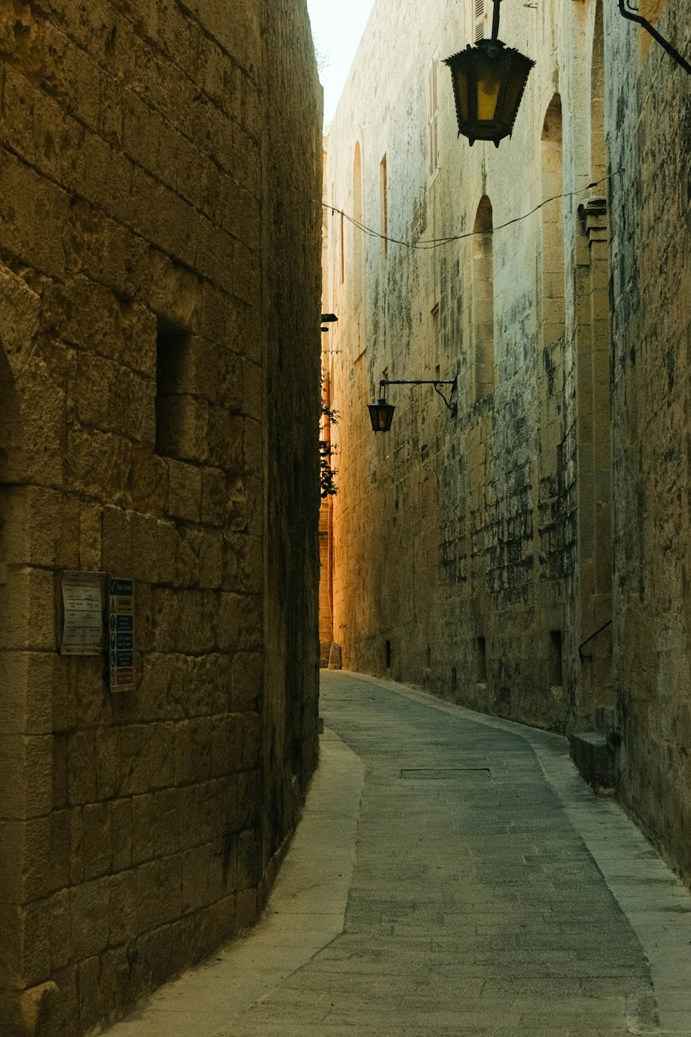 a narrow alley way with a lamp on the side