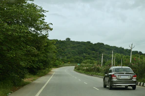 A Veloceway taxi cruising along a scenic road near Lymington with lush greenery around.