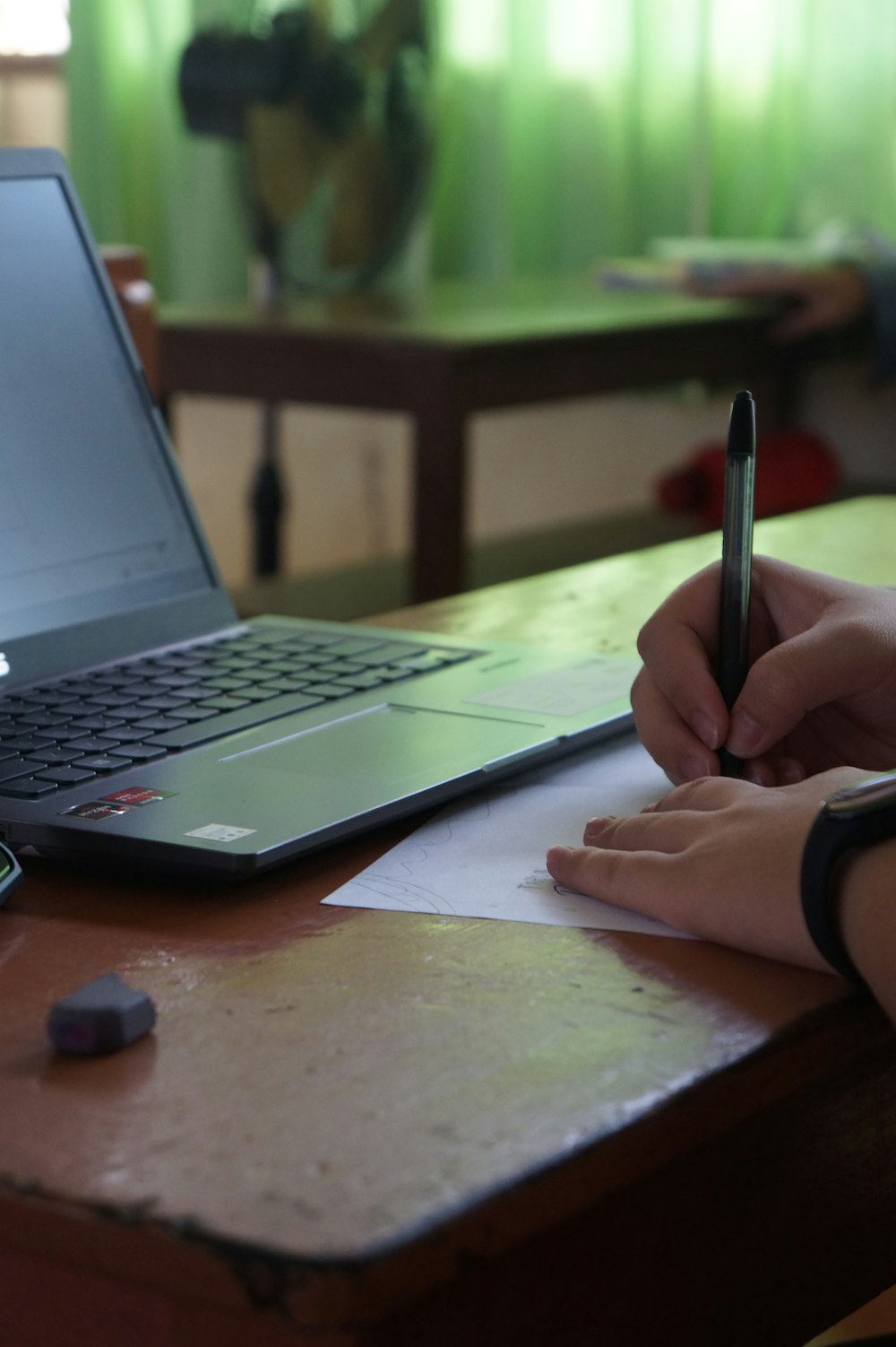 a person writing on a piece of paper next to a laptop