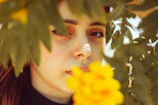 A candid portrait of a smiling woman framed by lush greenery.