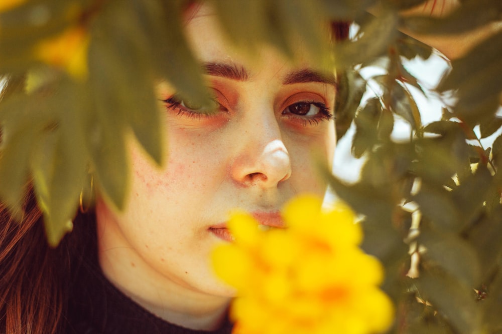 a woman is looking through the leaves of a tree