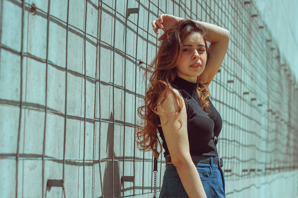 a woman leaning against a wall with her hand on her head