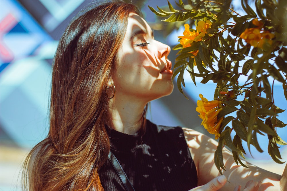 a woman smelling a tree with yellow flowers