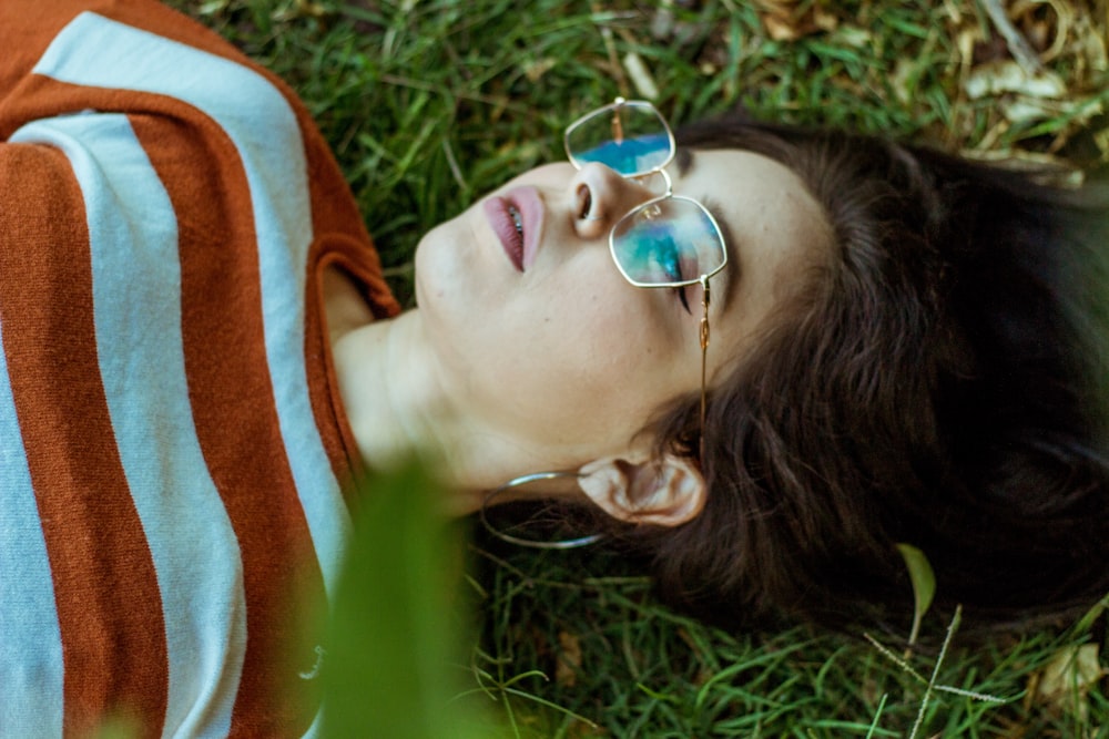 a woman laying on the grass wearing sunglasses