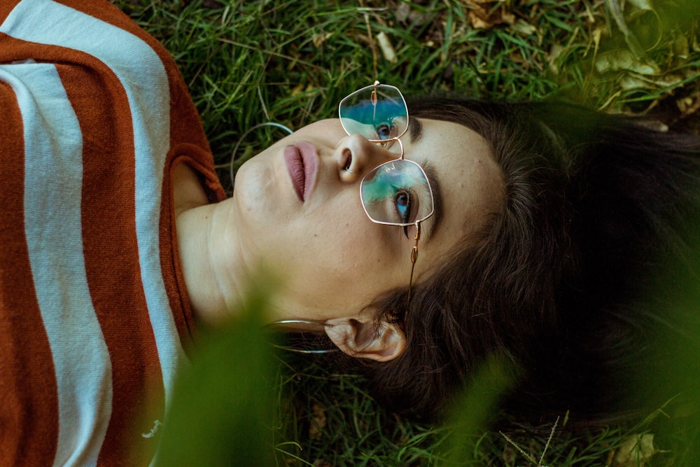 a woman laying in the grass with her eyes closed