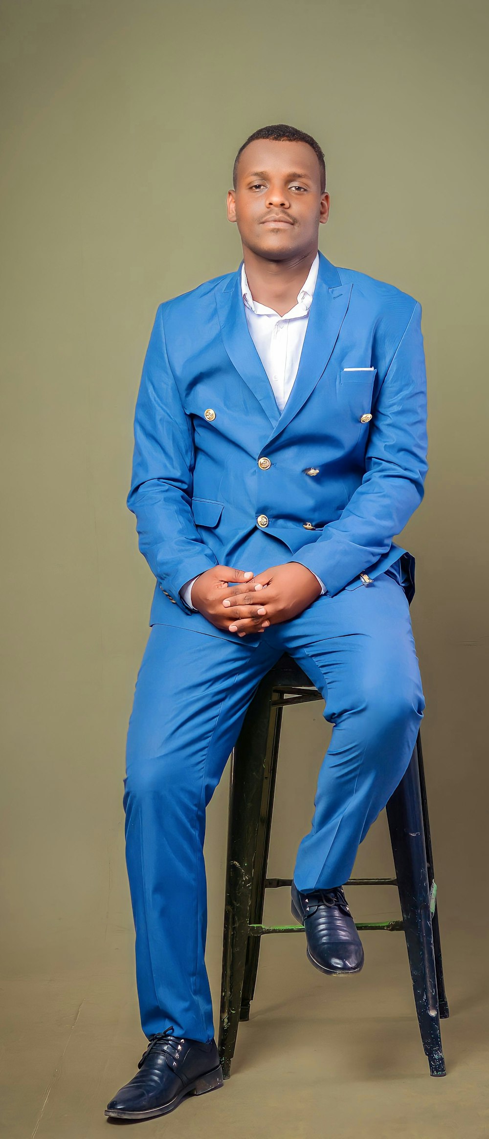 a man in a blue suit sitting on a stool