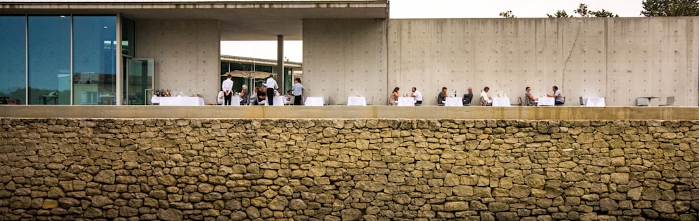 a group of people standing next to a stone wall