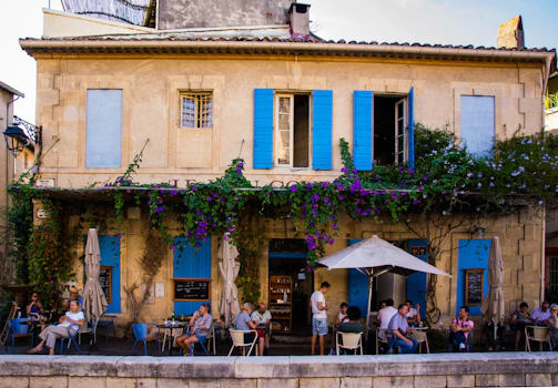A cozy café terrace overlooking a serene French vineyard at sunset.