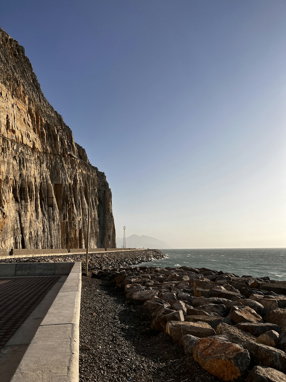 a rocky beach next to the ocean under a blue sky