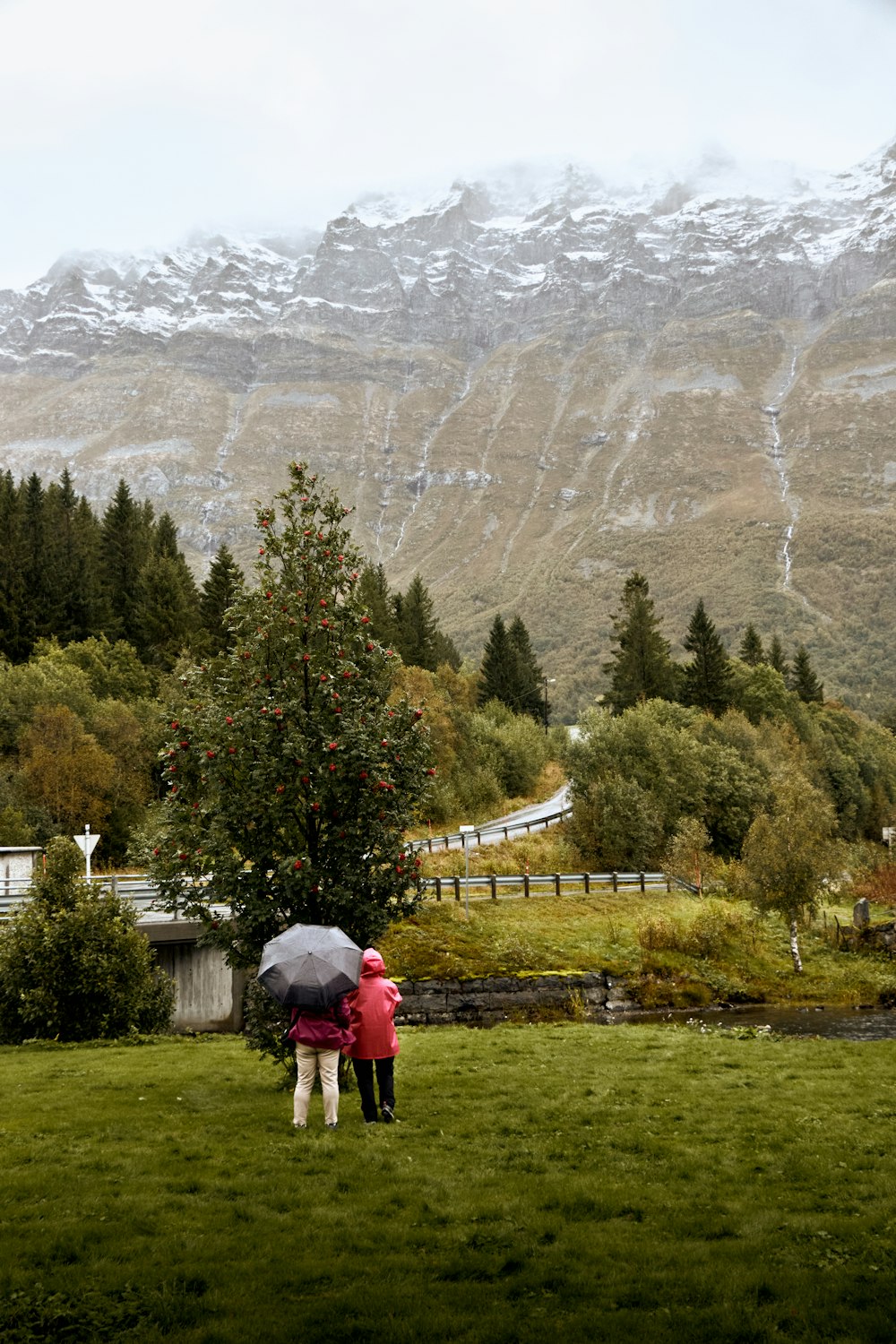 two people standing under an umbrella in a field