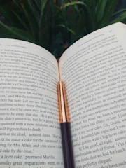An open book with philosophical quotes highlighted, next to a vintage fountain pen.