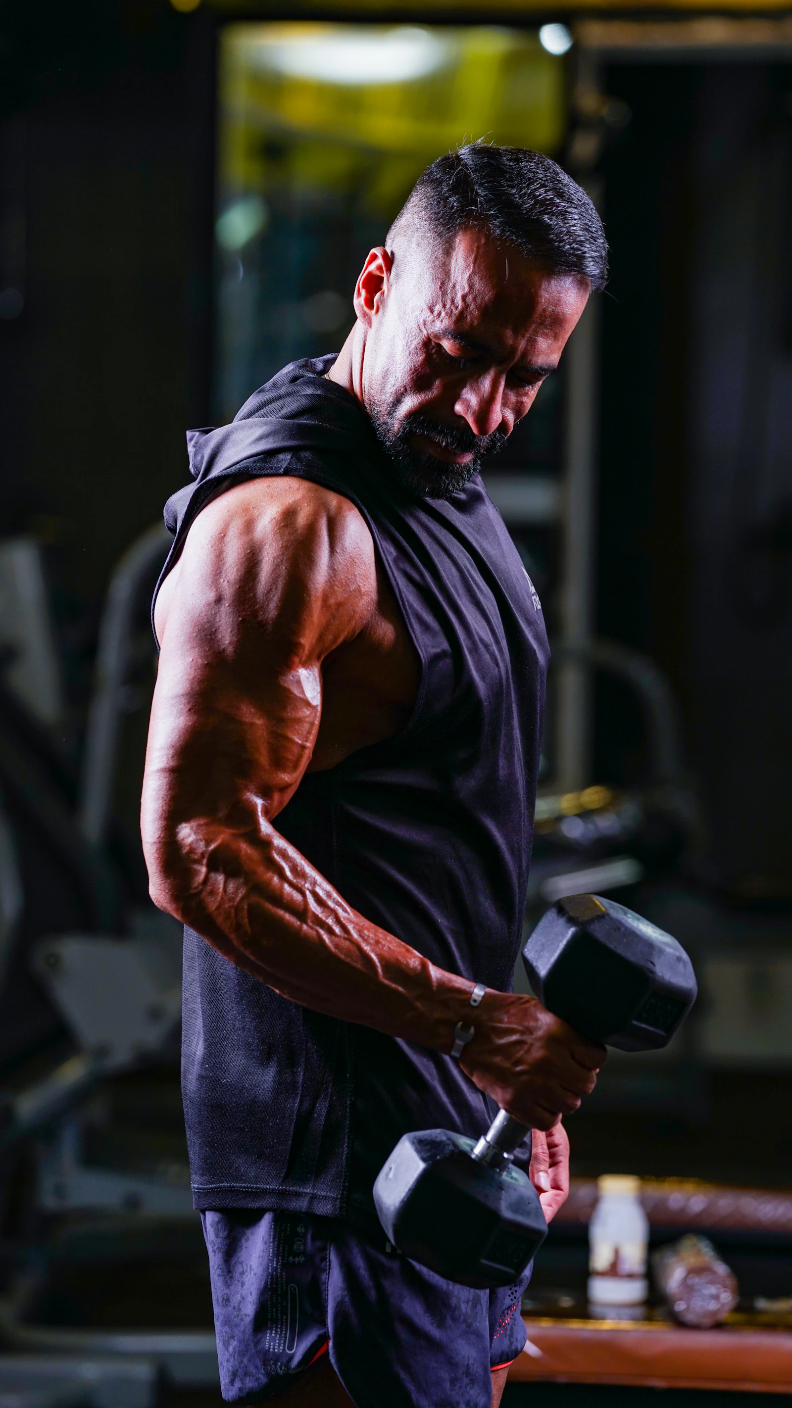 Atleta master fazendo rosca com halter, academia dramática