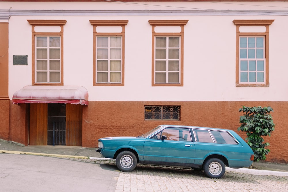 a blue car parked in front of a building