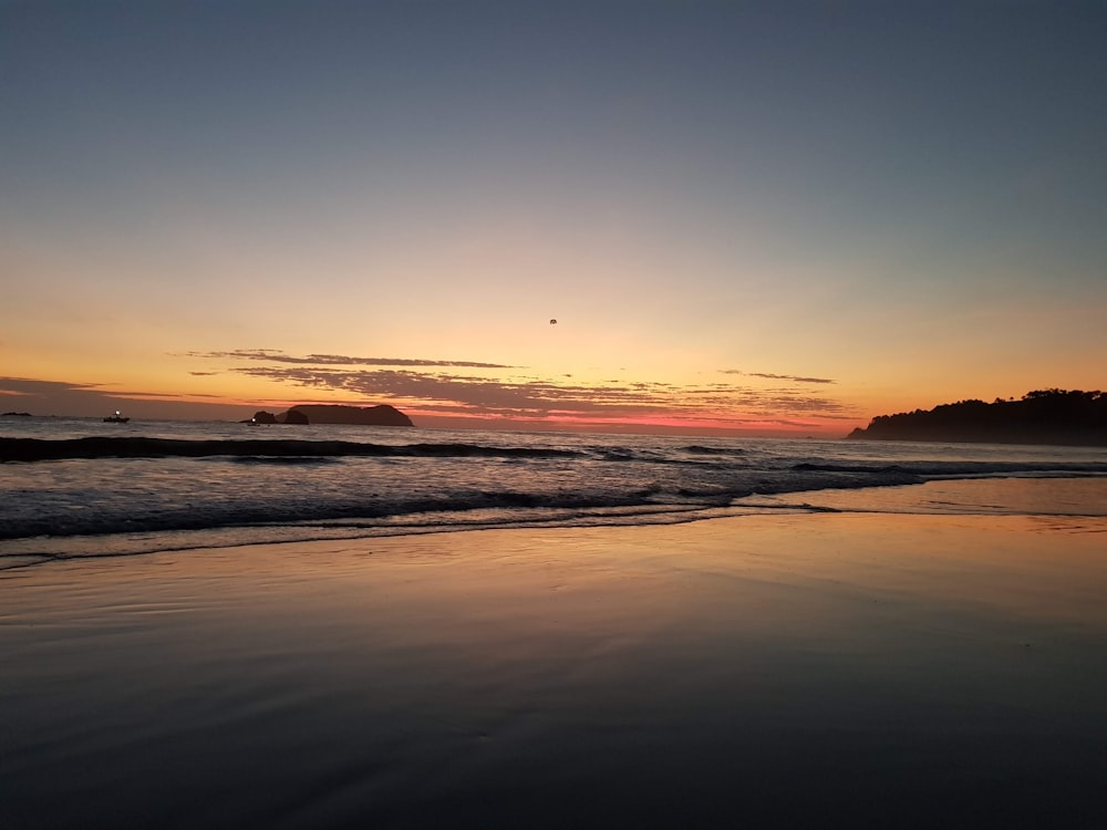 the sun is setting over the water at the beach