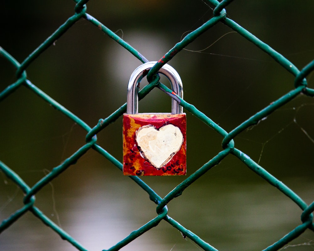 a heart shaped padlock attached to a chain link fence