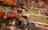A weathered brick wall with areas of erosion and wear shows patches of vibrant green leaves growing through the cracks, suggesting resilience and life emerging amidst decay.