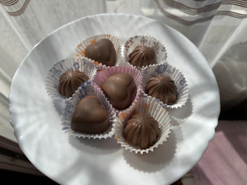 Delicate chocolate pralines arranged on a fine porcelain plate with a cup of coffee