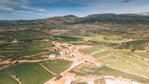 A scenic view of a village with farmers tending to their livestock under a clear blue sky.