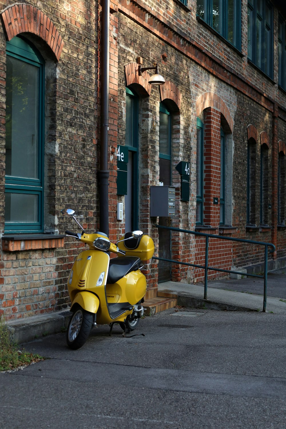 a yellow scooter parked in front of a brick building
