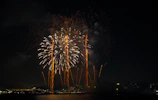 A vibrant burst of golden fireworks lighting up a night sky over a city skyline.