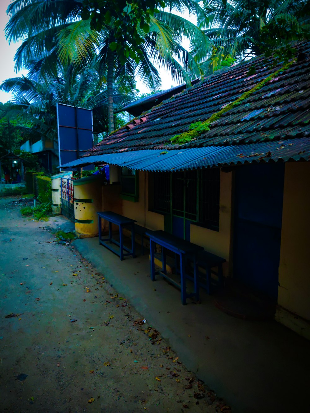 a yellow building with a blue roof and a blue bench