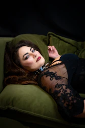 A sensual woman lounging on a velvet sofa, exuding charm and allure.
