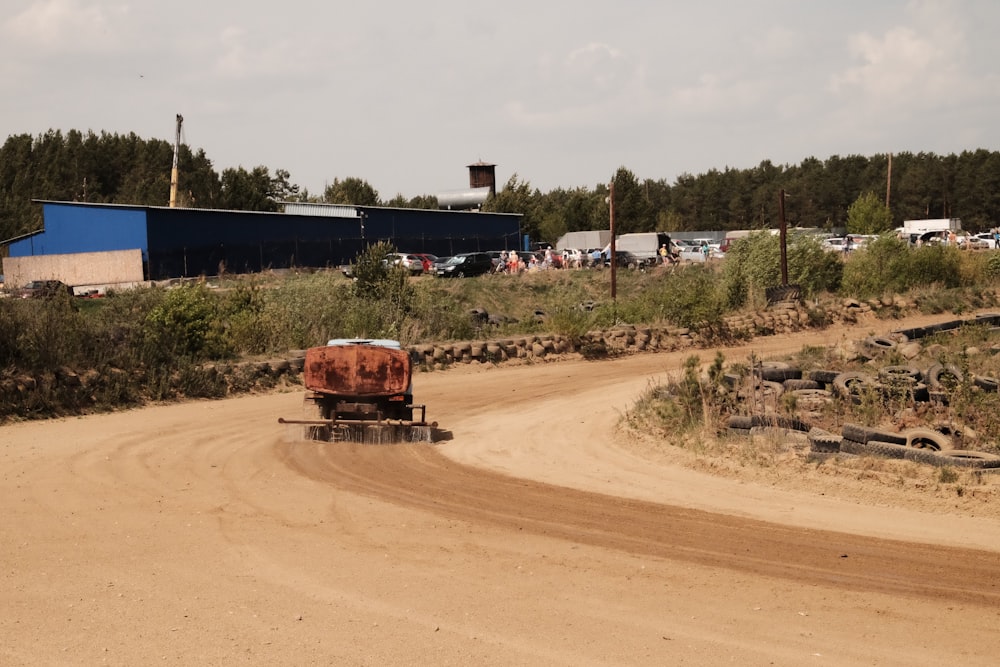 a truck driving down a dirt road next to a forest