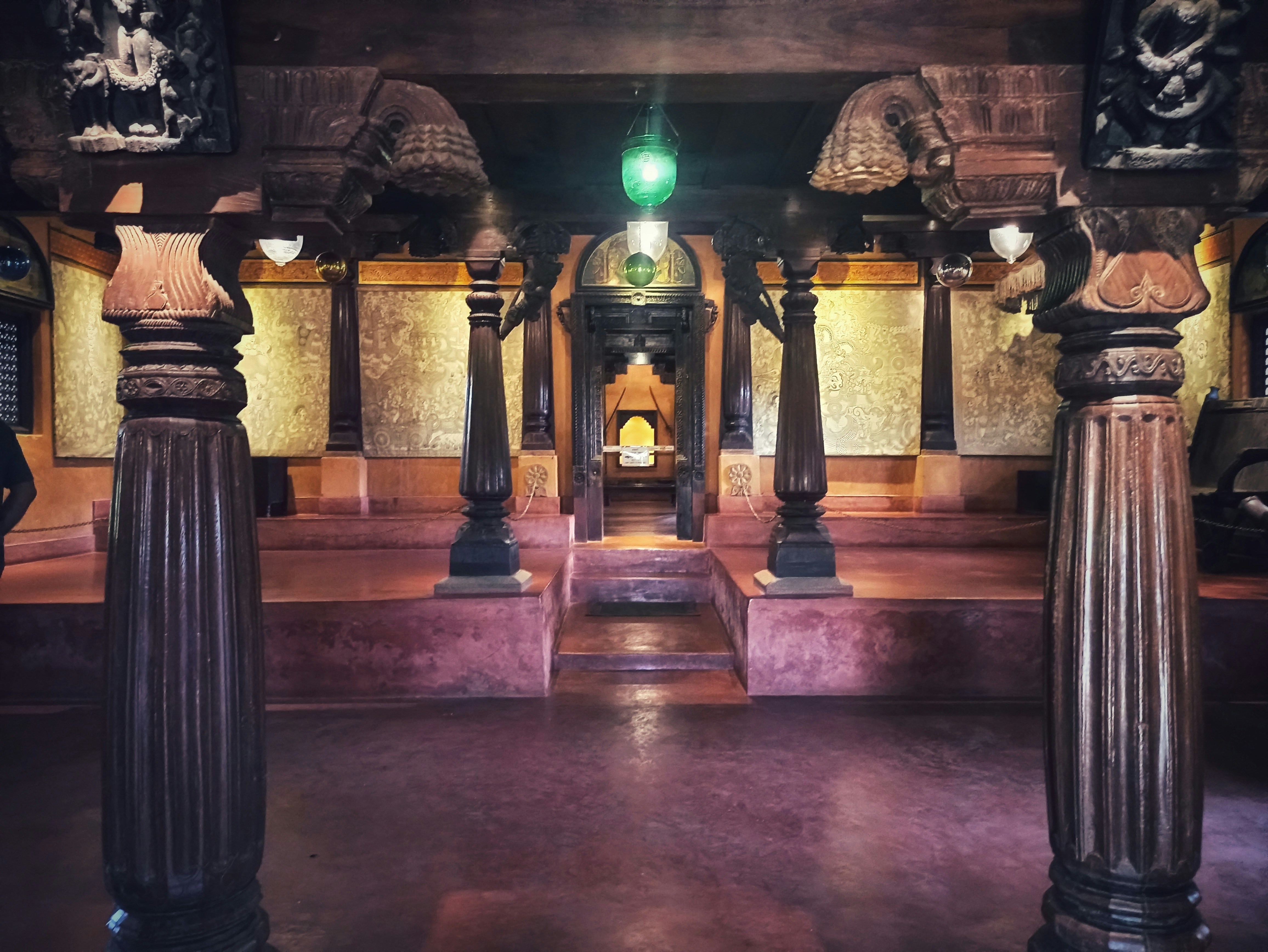 Temple interior with glowing lamps, dark atmospheric stone walls, flickering sacred fire