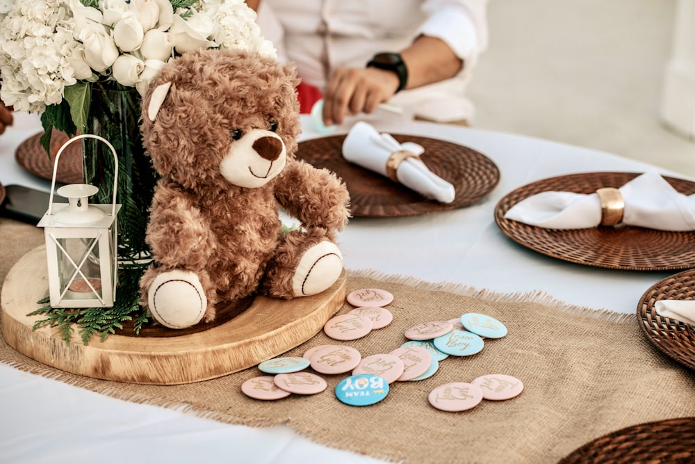 Un orsacchiotto seduto su un tavolo con un vaso di fiori