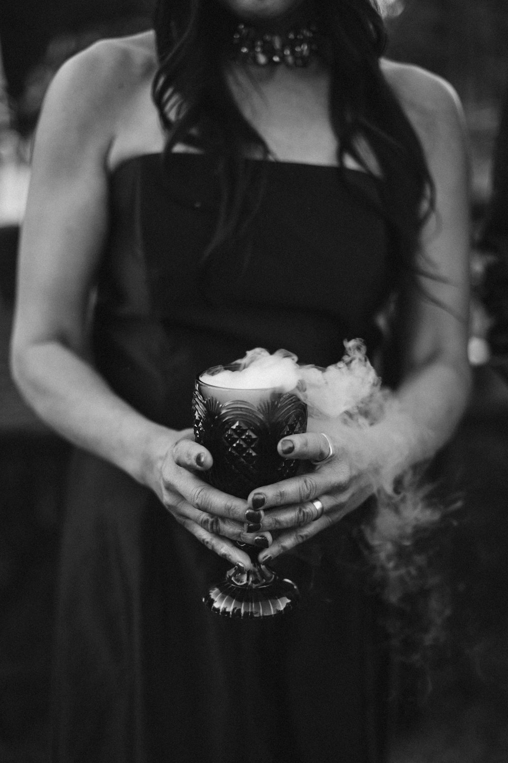 a woman in a black dress holding a cup