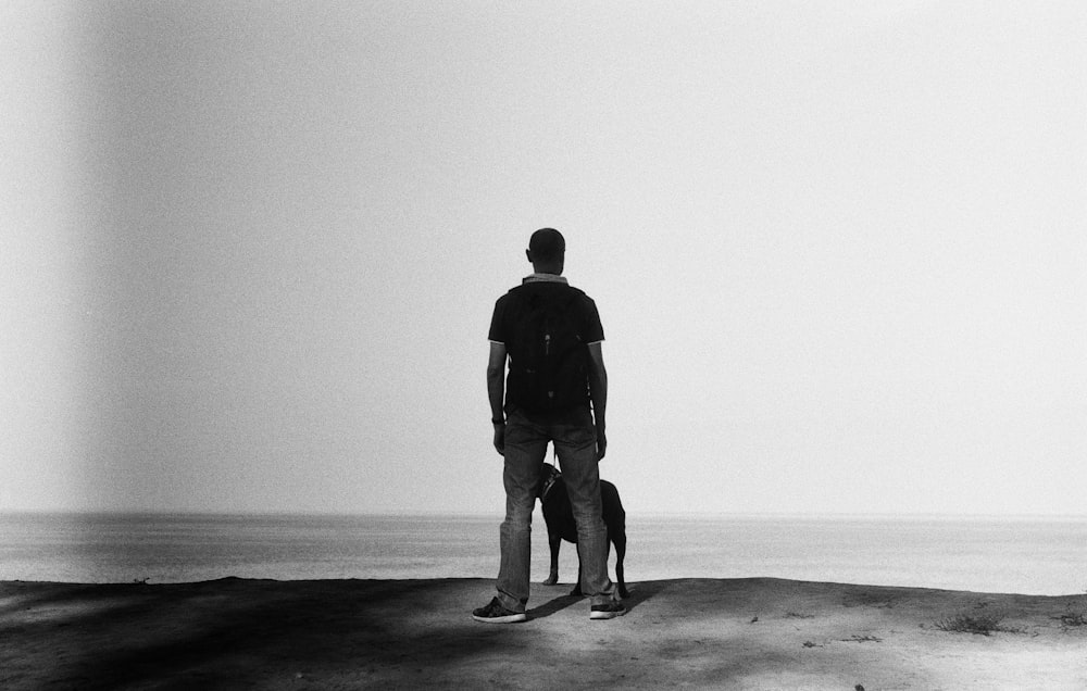 a man standing on top of a hill next to a dog