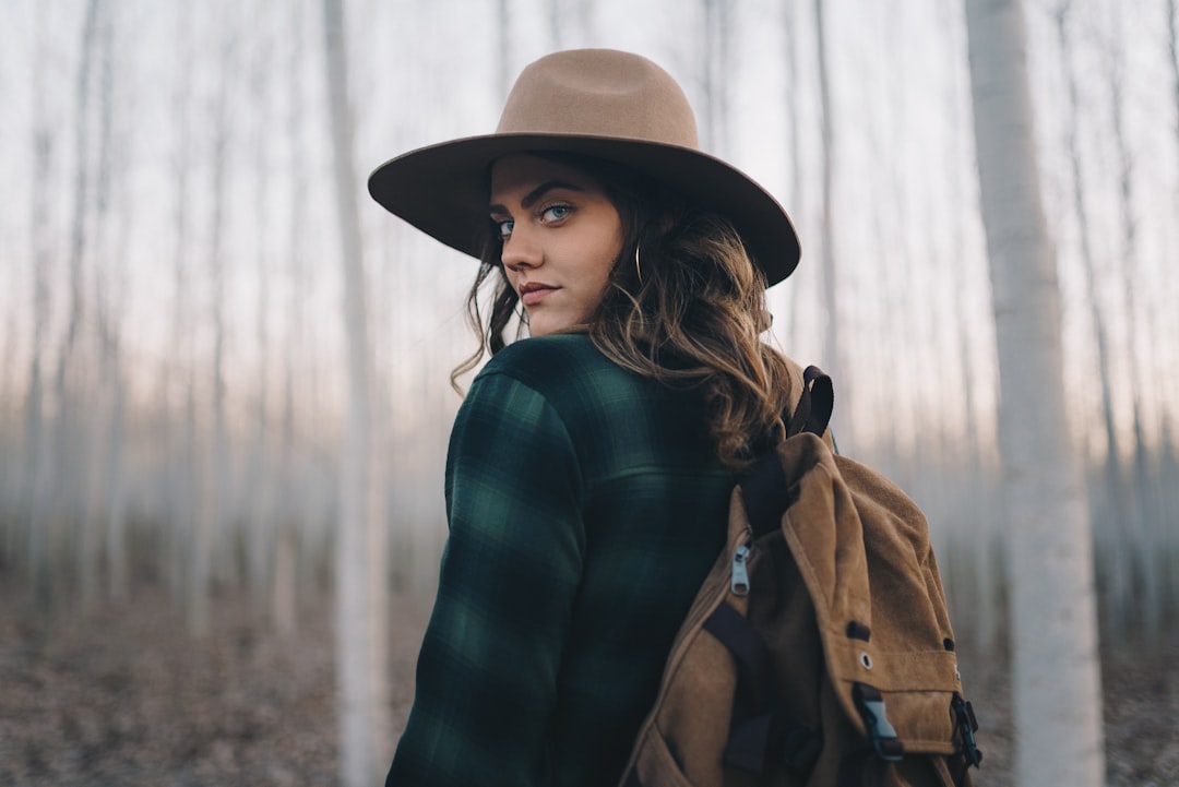 a woman wearing a hat in a forest, Follow me