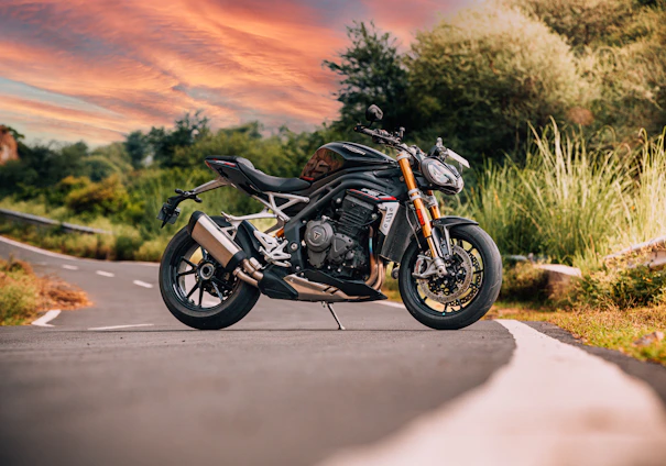 A sleek motorcycle parked on a winding jungle road with misty mountains in the background at dawn.