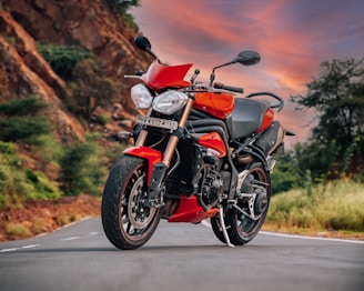 A red motorbike parked beside a scenic mountain overlook at sunset.
