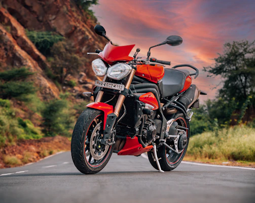A sleek red Honda motorcycle parked on a scenic mountain road at sunset.