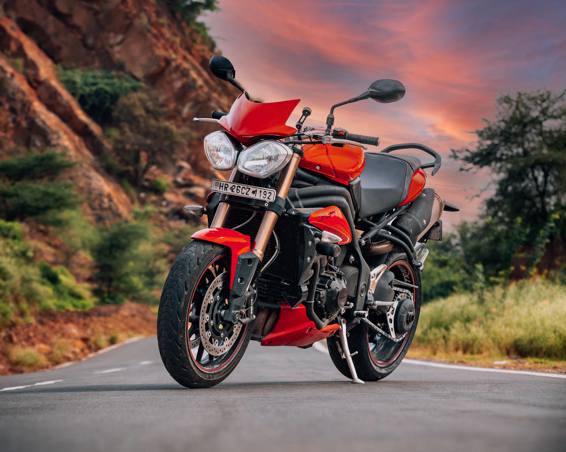 A vibrant red motorcycle speeding along a coastal road with the ocean and cliffs in the background.