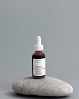 a bottle of vitamin oil sitting on top of a rock