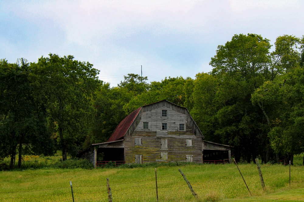 an old barn in the middle of a field