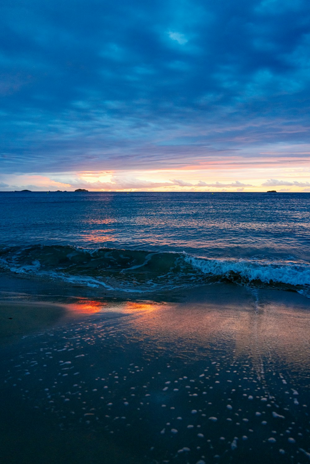 the sun is setting over the ocean on the beach