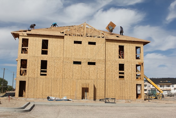 A team of construction workers from Harbor Companies collaborating on a residential roofing project under clear skies.
