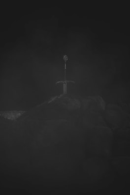 A close-up of a sword embedded in a stone.