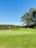 A lush green golf course with well-maintained fairways and a clear blue sky.
