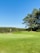 A lush green golf course with well-maintained fairways and a clear blue sky.