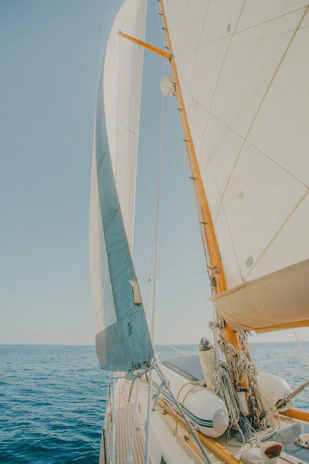 Close-up of a white sail catching the wind against a deep blue sea background.