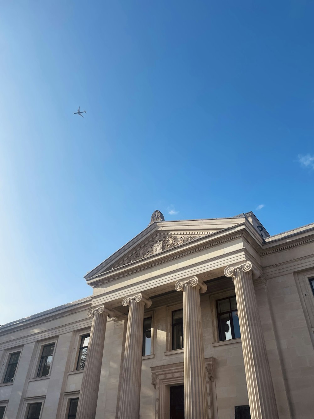 a large building with columns and a plane in the sky