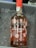 A bottle of Port Wine labeled 'DELAFORCE' with 'Rosé' below it is placed in a container filled with ice. The bottle has a red cap and is adorned with illustrations of various fruits such as cherries, watermelon slices, strawberries, oranges, and kiwis. There are visible liquid droplets on the bottle due to the cold ice.