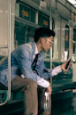 a man sitting on a train looking at his cell phone